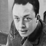 Albert Camus - Albert Camus, gagnant de prix Nobel, portrait en buste, posé au bureau, faisant face à gauche, cigarette de tabagisme, tags: manuskript von der fremde - CC BY-SA