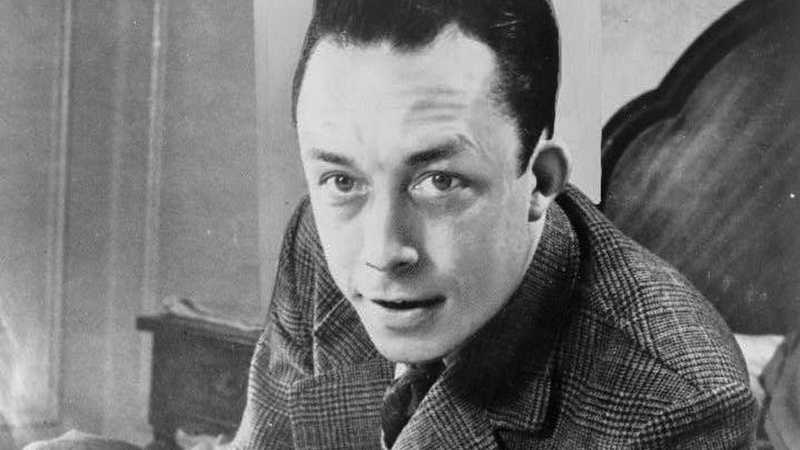 Albert Camus - Albert Camus, gagnant de prix Nobel, portrait en buste, posé au bureau, faisant face à gauche, cigarette de tabagisme, tags: manuskript von der fremde - CC BY-SA